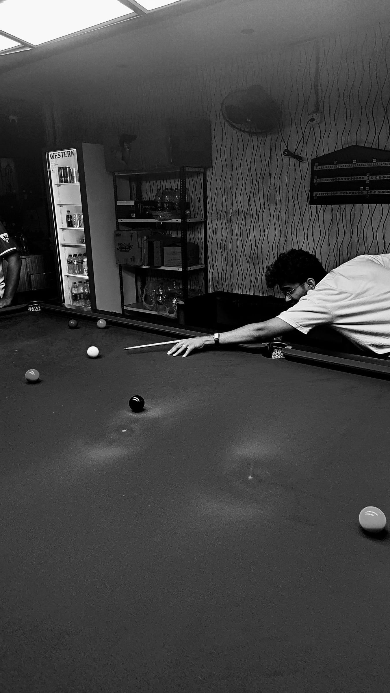 Black-and-white shot of someone lining up a shot at a pool table